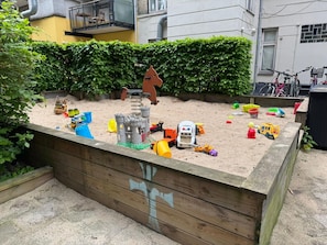 A sandbox play area with toys and a wooden play structure.