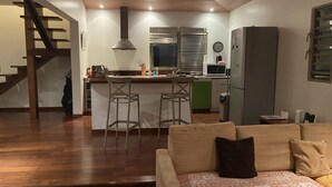 A modern kitchen with a central island, bar stools, a refrigerator, and a microwave.