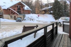 A wooden cabin with a snow-covered roof, a car parked in front, and a no parking sign.