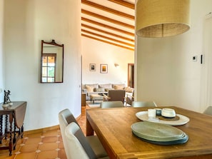 Un comedor con mesa de madera, sillas y una lámpara colgante.
