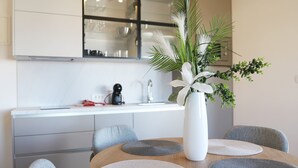 A modern kitchen with white cabinets, a glass backsplash, and a dining area with a round table and grey chairs.