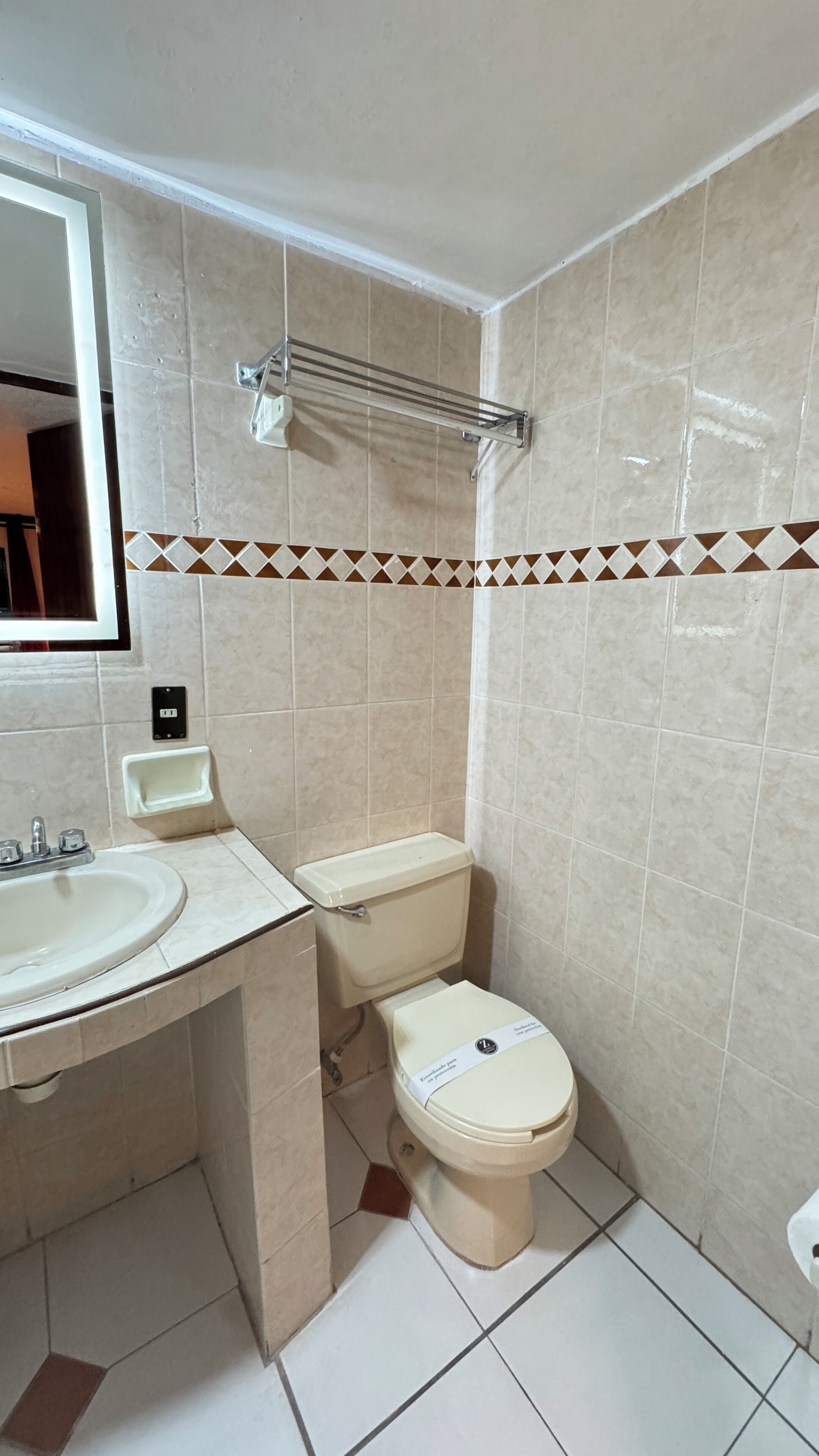 A small bathroom with a sink, toilet, and mirror.