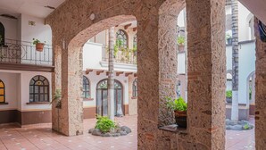 Un pati amb arcs de pedra, plantes en testos i un paviment de rajoles.