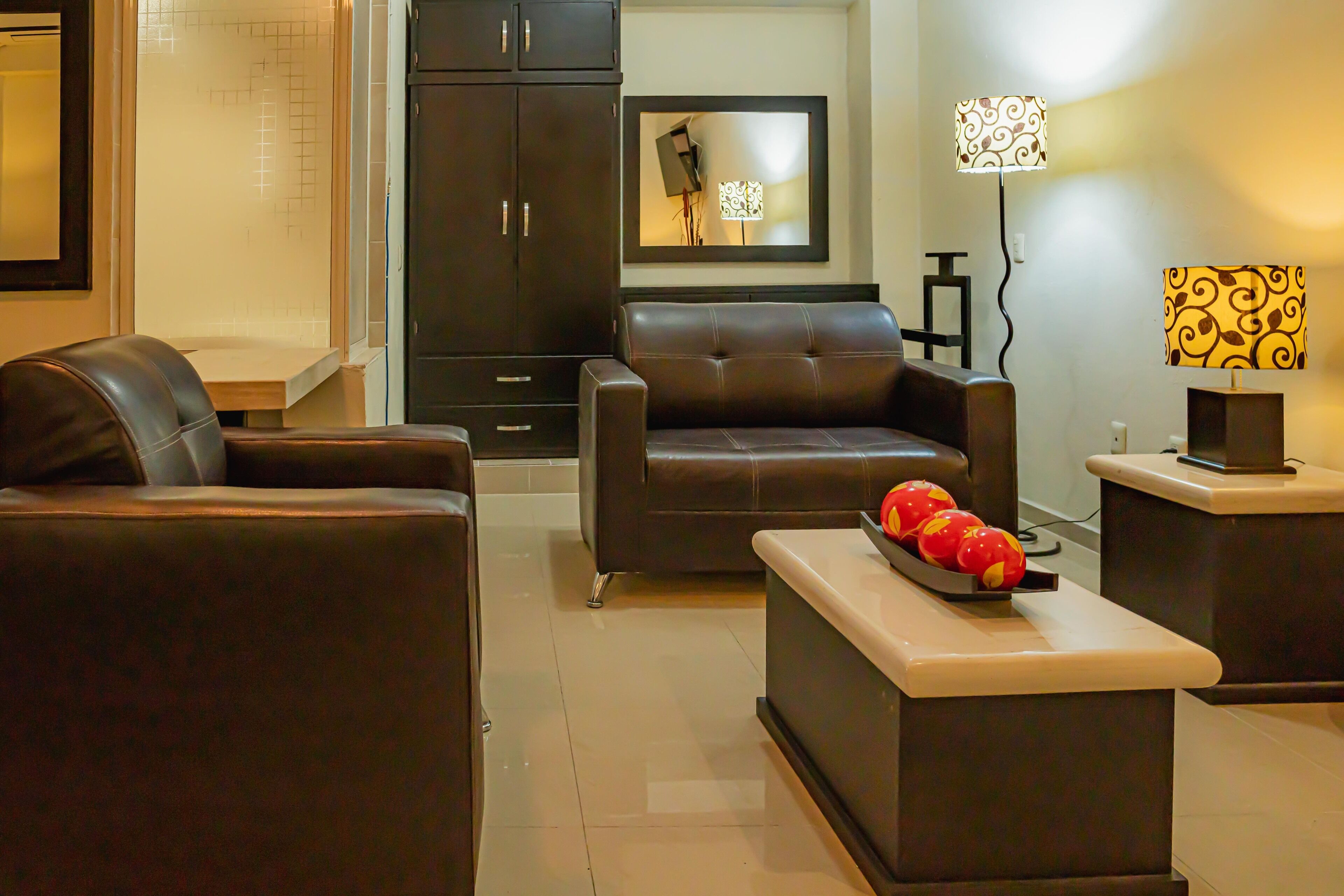A modern living room with a sofa, a coffee table with fruit, a cabinet, and a lamp.