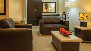 A modern living room with a sofa, a coffee table with fruit, a cabinet, and a lamp.