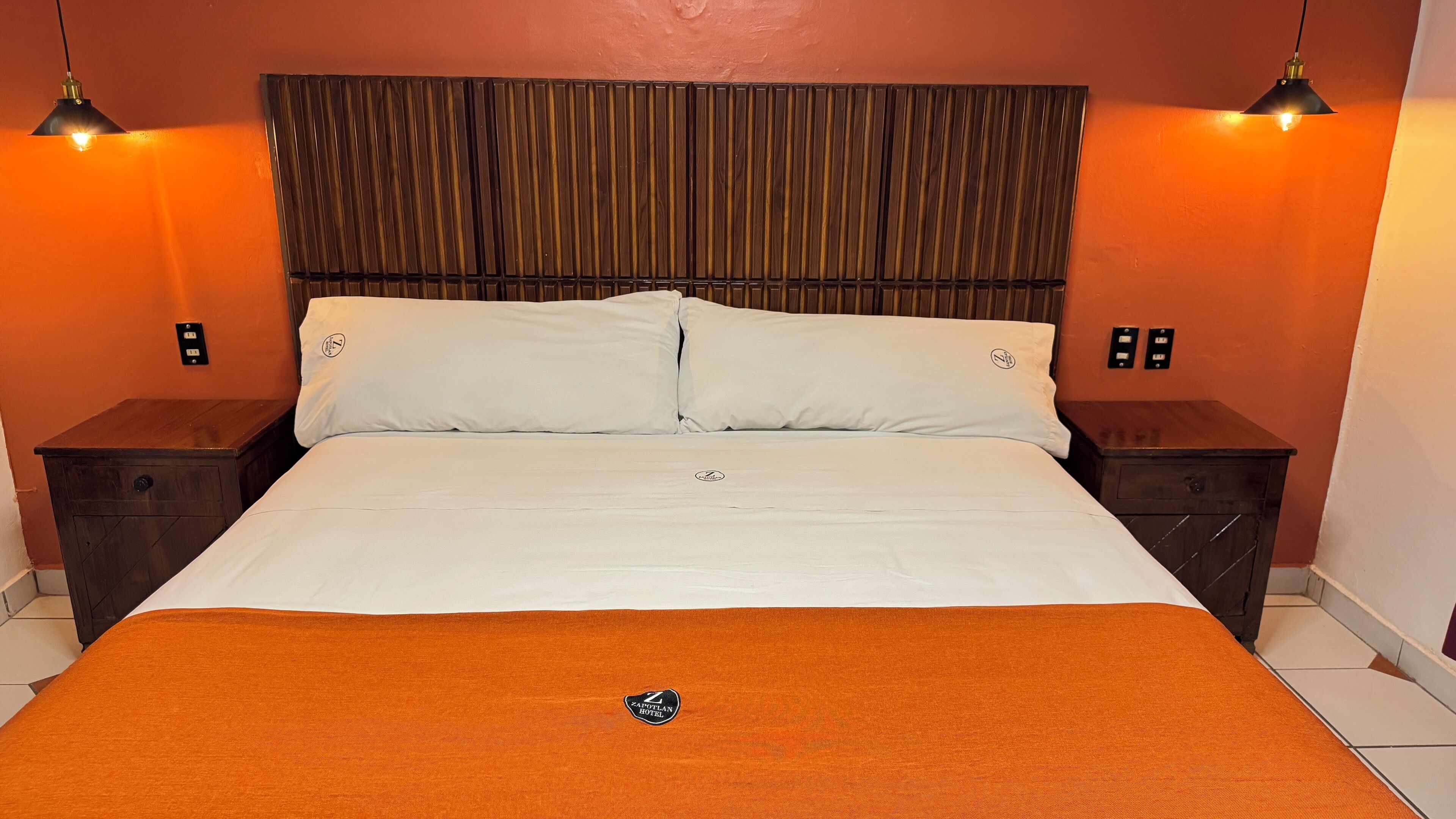 A hotel room with a bed, two nightstands, and a headboard.