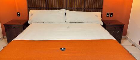 A hotel room with a bed, two nightstands, and a headboard.