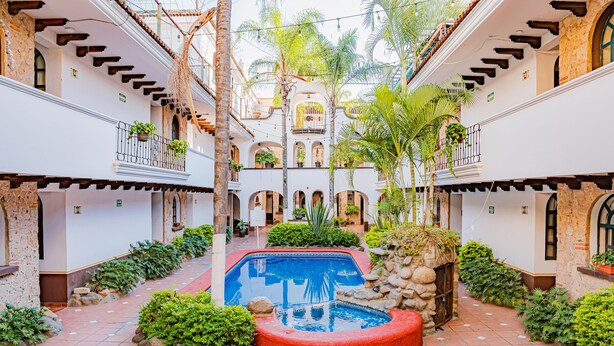 Un pati amb piscina, envoltat de plantes i parets de pedra.