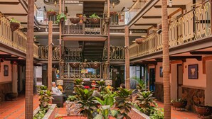 Un atrium multi-nivell amb sostre de vidre, balcons amb planters penjants i un planter central amb diverses plantes.