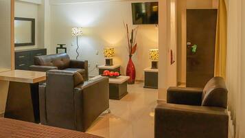 A modern hotel room with a large bed, a desk, a sofa, and a TV.