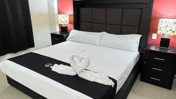 Camera d'albergo con un letto, comodini neri, una parete rossa con motivi a foglia e un condizionatore d'aria.