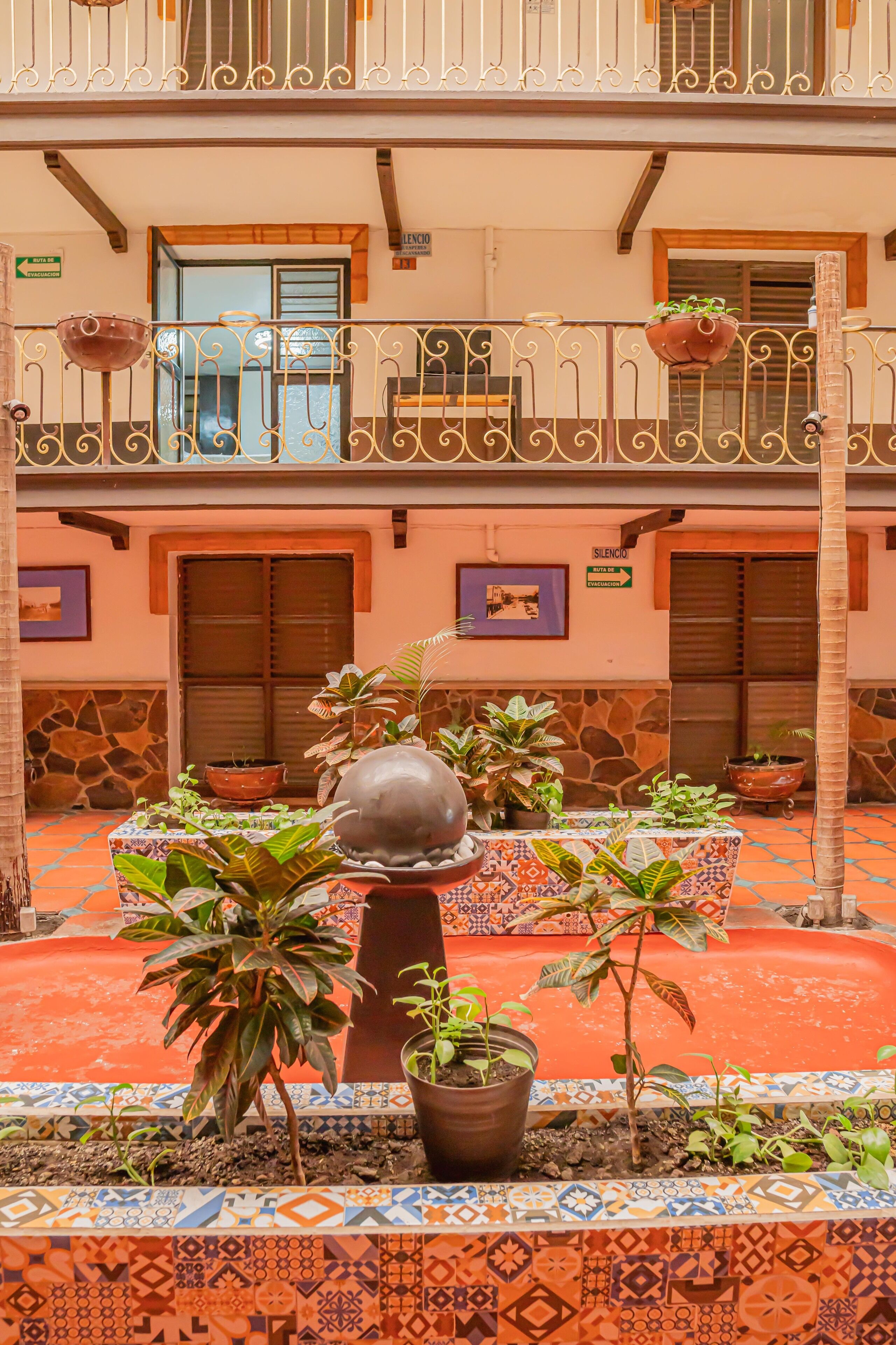 Un patio con una fuente, plantas en macetas y suelo de baldosas.