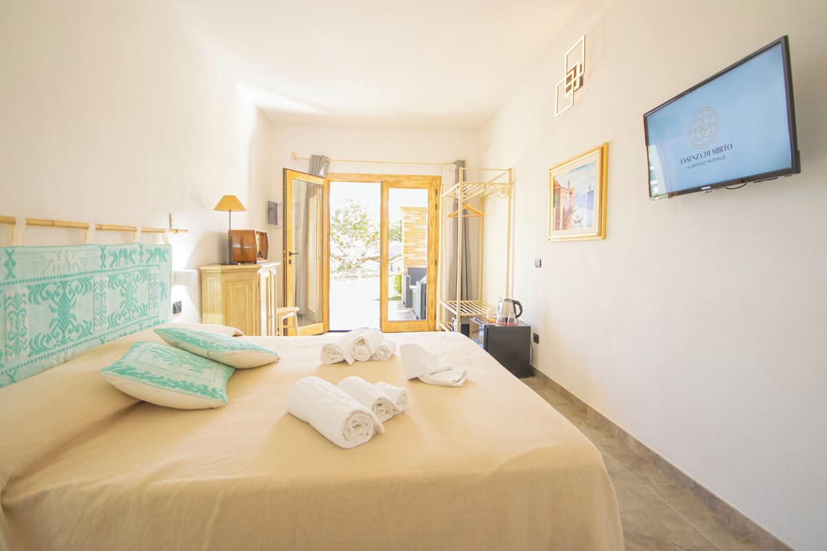 Une chambre d’hôtel avec un lit, une télévision, une porte donnant sur l’extérieur et une vue sur l’extérieur.