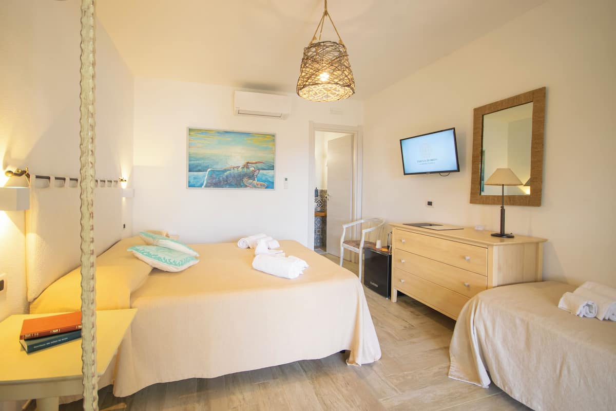 Une chambre d’hôtel comprenant un lit, des tables de chevet, un bureau, une chaise, une commode, un téléviseur et un tableau au mur.