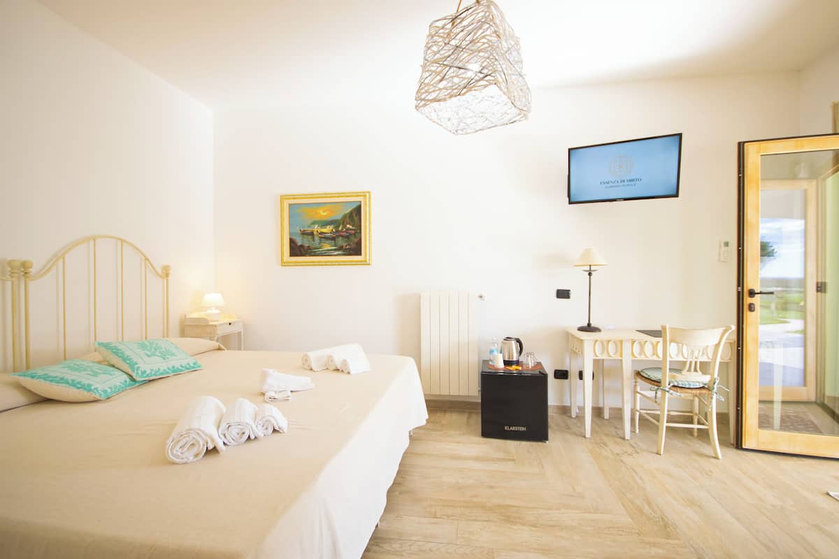 Une chambre d’hôtel avec un lit, un bureau, une chaise, une télévision et un tableau au mur.