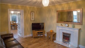 Una sala de estar con televisión, chimenea y candelabro.