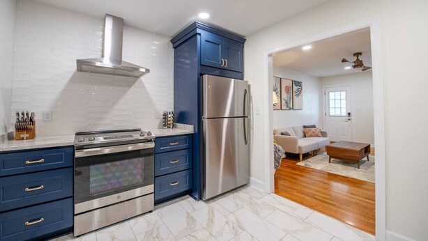 A modern kitchen with stainless steel appliances, blue cabinets, and a white tiled backsplash. - Midtown Cottage - Central Location! 😍 (Duplex) (Tallahassee)