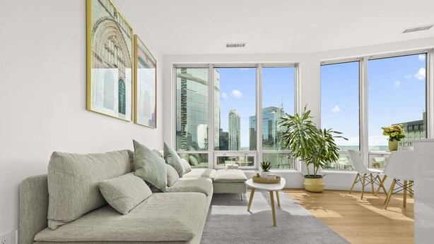 A modern living room with a grey sofa, a small round table, and a potted plant. - 2 BR Downtown Oasis, AC & stunning views (Vancouver)