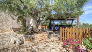 Une cour dallée de pierres, agrémentée d’une pergola, d’une clôture en bois et de plantes en pot.
