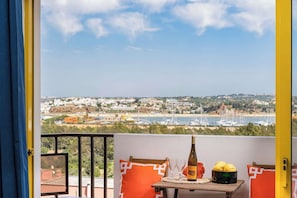 Enjoy a glass of wine on the balcony with a view of the coastal town's beach, boats, and homes.