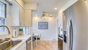Una cocina moderna con un refrigerador de acero inoxidable, un horno empotrado y un ventilador de techo.