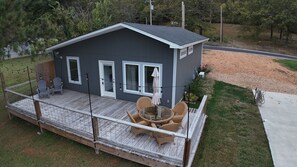 Une petite maison de plain-pied avec un porche, une terrasse et un petit jardin.