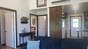 Un salon moderne avec un canapé gris foncé, un coussin décoratif et une citation encadrée accrochée au mur.