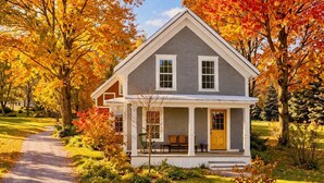 A two-story house with a front porch, a driveway, and autumn foliage. - Charming Chester Farmhouse near Near VT Slopes (Chester)
