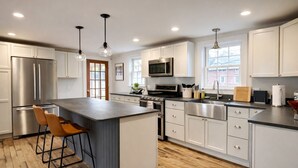 A modern kitchen with a central island, stainless steel appliances, and pendant lighting. - Charming Chester Farmhouse near Near VT Slopes (Chester)