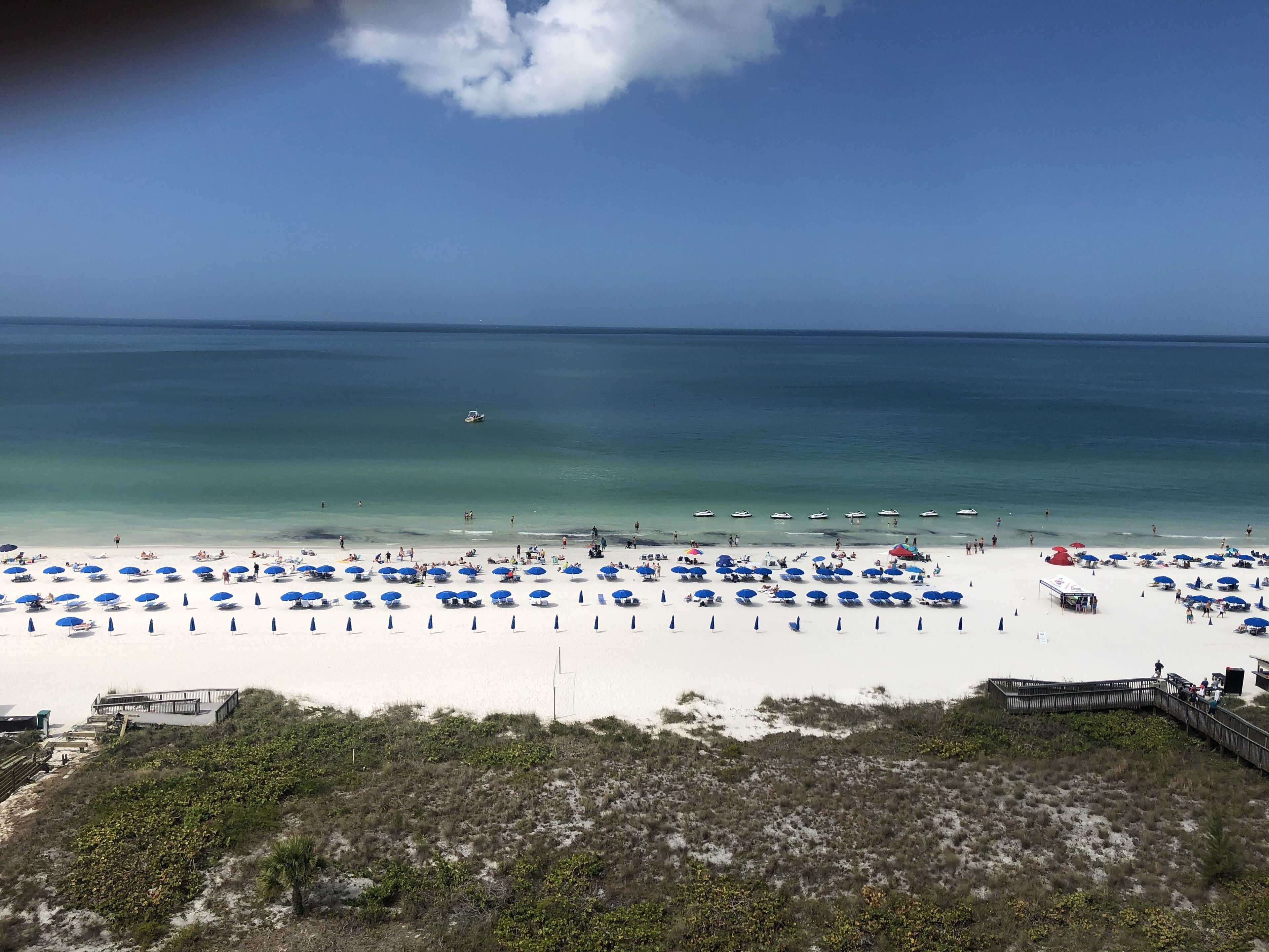 Ein Strand mit blauen Sonnenschirmen und weißem Sand.