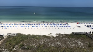 Ein Strand mit blauen Sonnenschirmen und weißem Sand.
