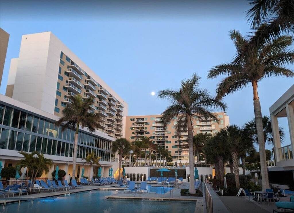 Un hotel con piscina, palmeras y cielo despejado.