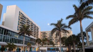 Ein Hotel mit Poolbereich, Palmen und blauem Himmel.
