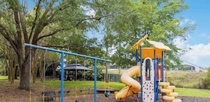 Un parque infantil con columpios, un tobogán y una estructura para escalar.