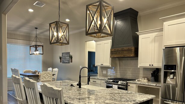 A modern kitchen with a central island, stainless steel appliances, and pendant lighting. - Charming Retreat in Hallsville, TX – Your Cozy Home Away from Home! (Hallsville)
