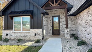 A two-story house with a dark wooden exterior and a stone facade. - Charming Retreat in Hallsville, TX – Your Cozy Home Away from Home! (Hallsville)