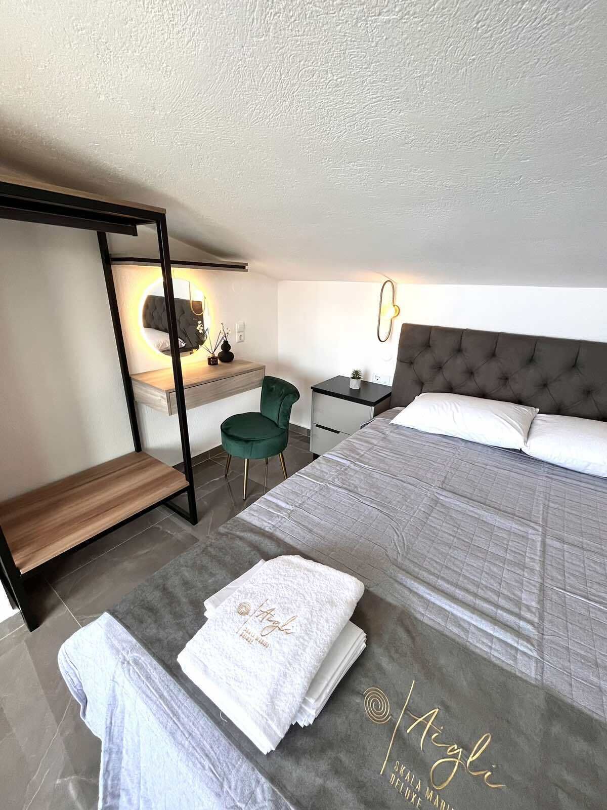 A modern bedroom with a bed, a desk, a chair, and a bedside table.