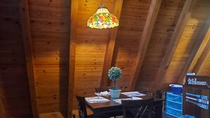 A wooden dining area with a table, chairs, a hanging stained glass light fixture, a small potted plant, and a welcome sign. - 2 wooded acres, 2 king beds & 1 full bed, fire pit & plenty of parking!  (Springville)