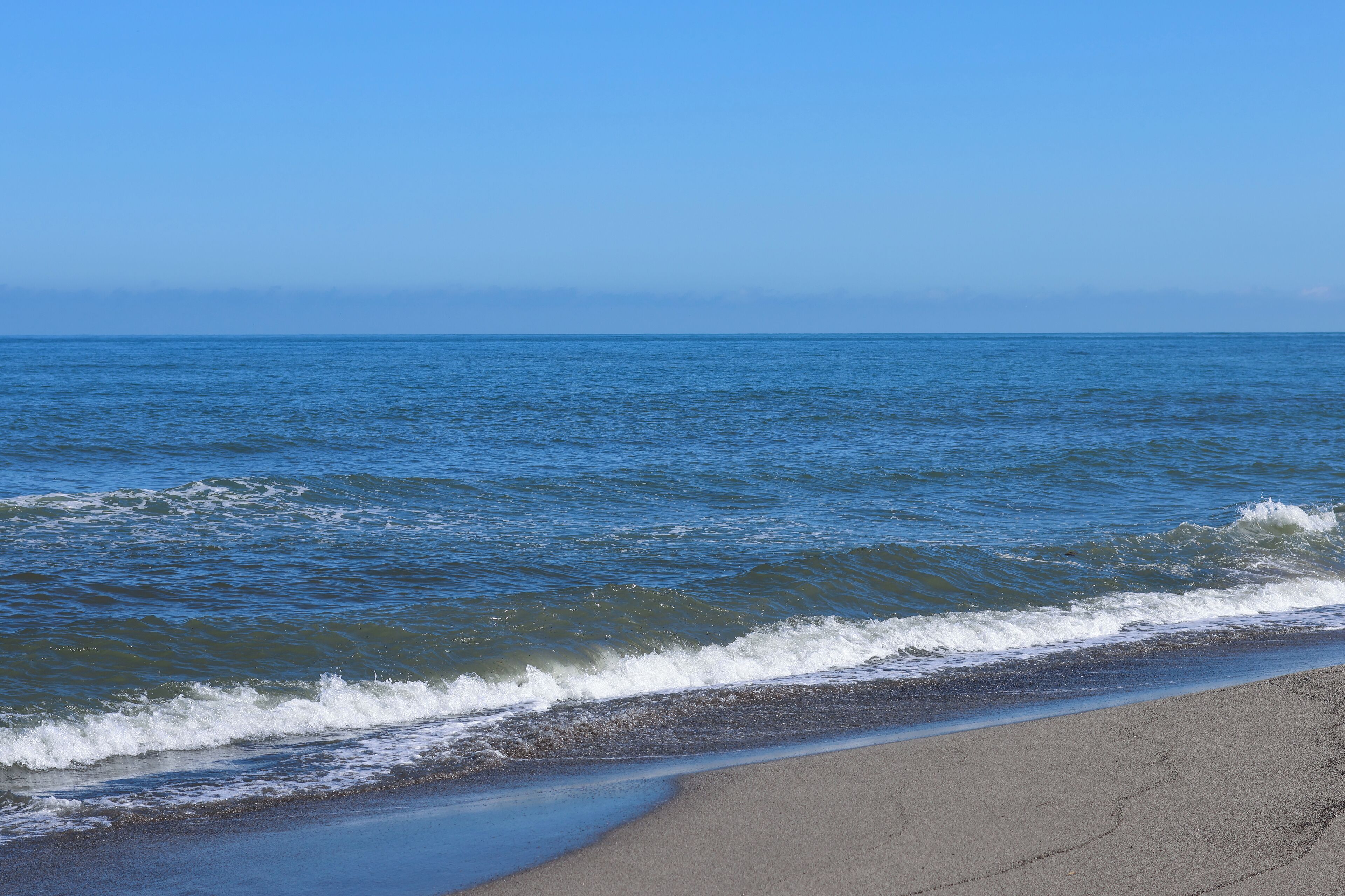 Une plage où les vagues viennent doucement lécher le rivage.