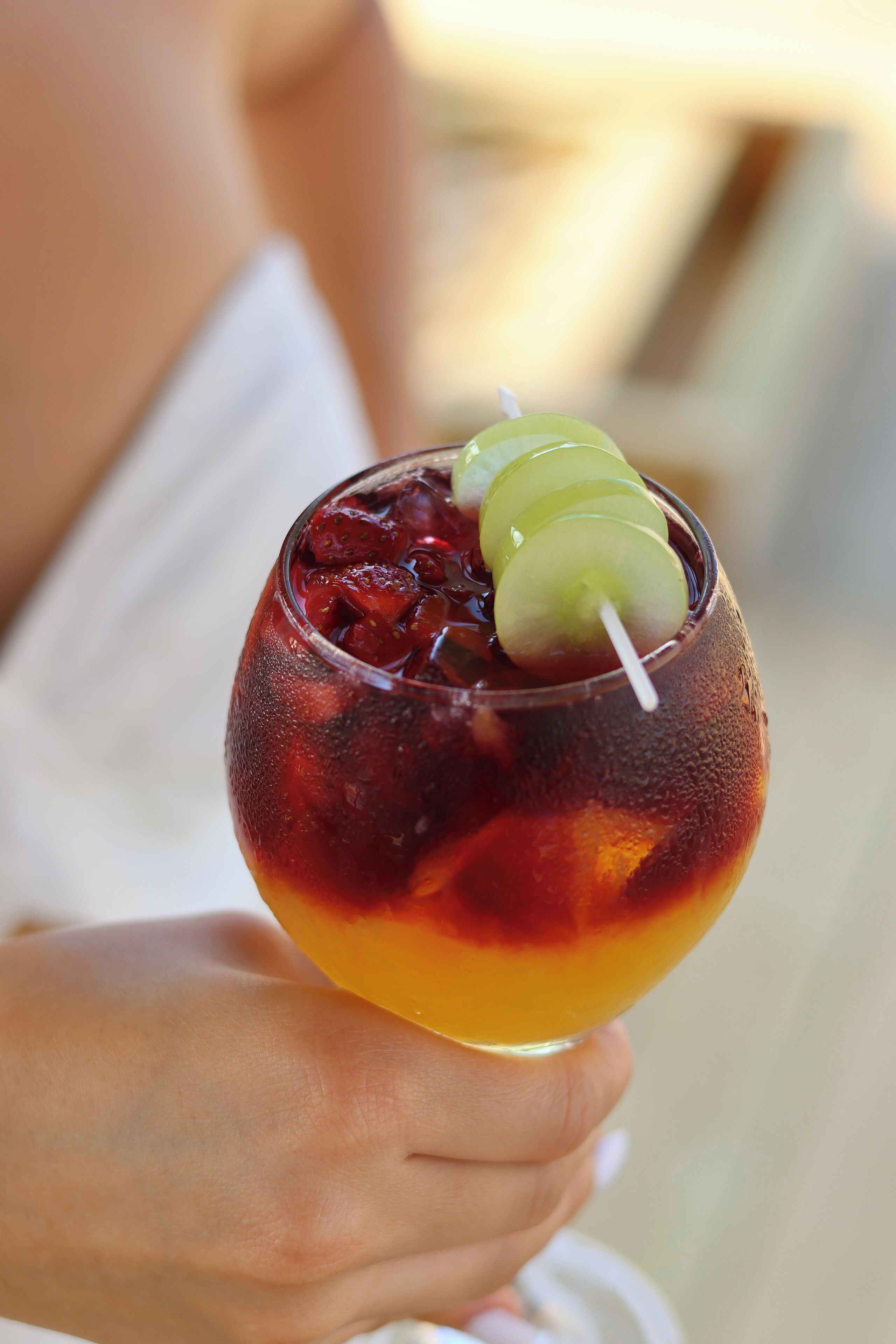 A person holding a cocktail with a lime garnish.