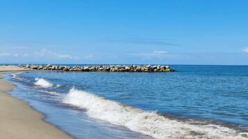 En privat strand, hvidt sand, liggestole, parasoller