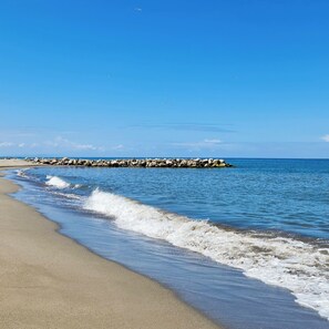 Een privéstrand, wit zand, ligstoelen aan het strand, parasols