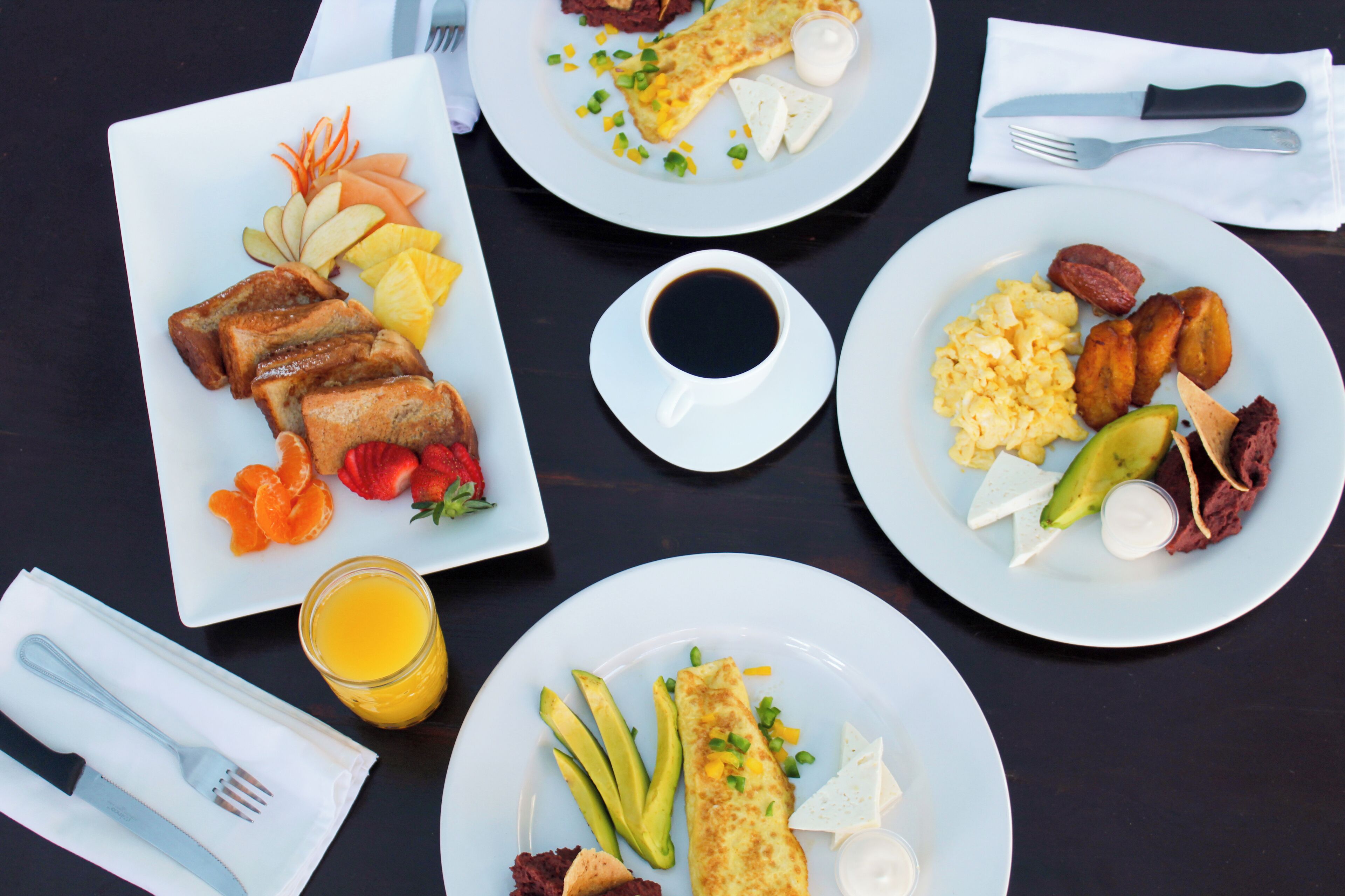 Mesa de café da manhã com vários pratos de comida, incluindo torradas, ovos e frutas.