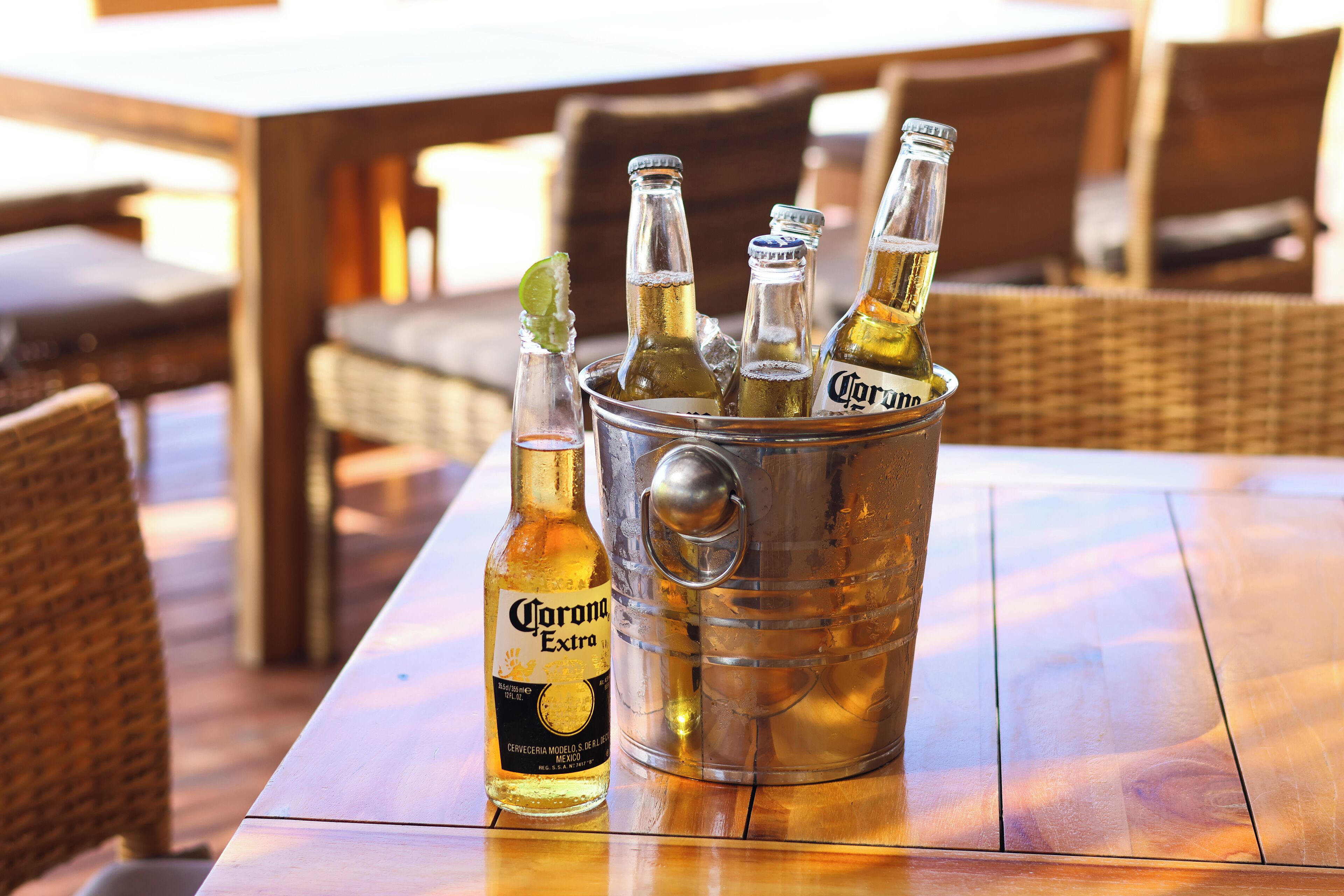 A table with a metal ice bucket containing bottles of Corona beer and a lime wedge.