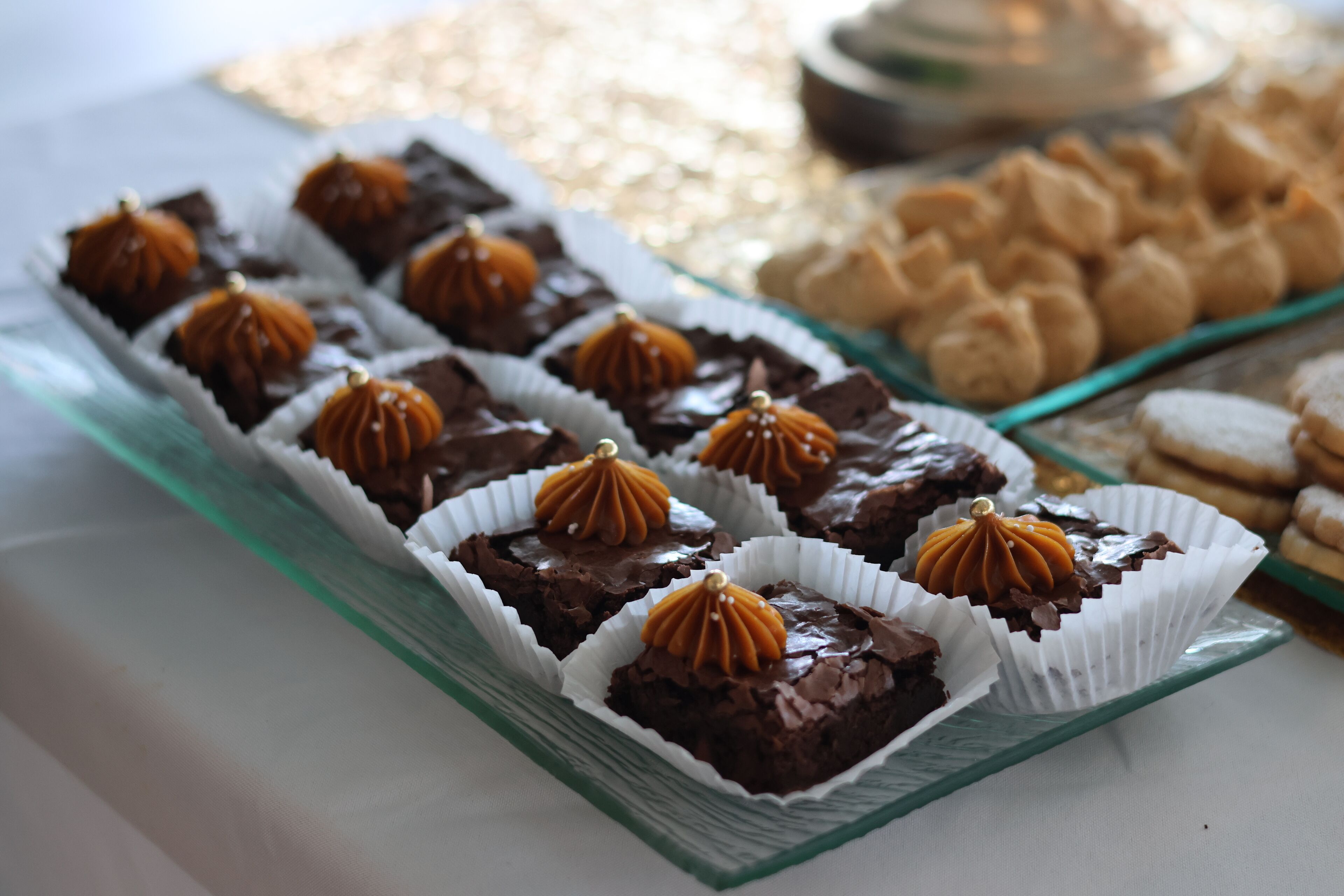 Een glazen serveerplank met chocoladedesserts en koekjes.