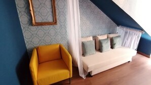 A room with a yellow armchair, a white sofa with cushions, a patterned wall, and a blue accent wall.