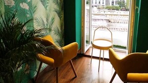 A room with a tropical wallpaper, a large window, and two yellow chairs.
