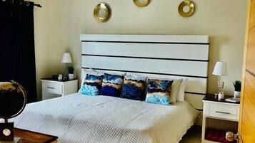 Un dormitorio con cama, mesitas de noche, ventilador de techo y adornos en la pared.