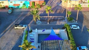 Vista aérea de una zona costera con edificios, palmeras y una playa.