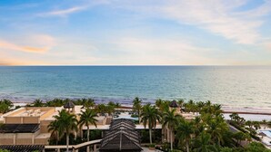 A resort with a pool area, palm trees, and a view of the ocean.
